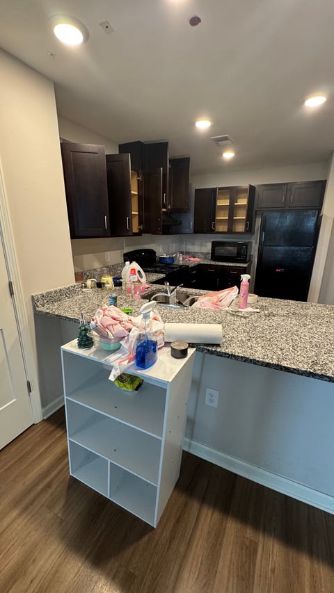 Modern kitchen with white island featuring granite countertop, dark black cabinets, stainless steel appliances, and recessed lighting