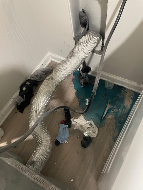 Overhead view of a window air conditioning unit installation with ductwork, hoses, and mounting hardware on wooden floor