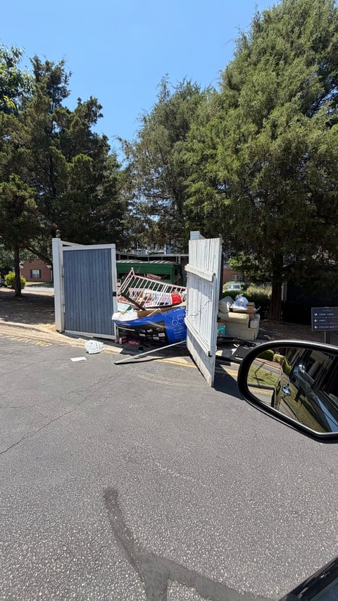 Open utility trailer with white metal doors containing blue kayak and paddle equipment parked under trees
